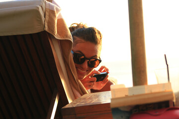 Young woman smiling at the poolside holding a cellphone