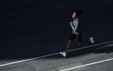 Fast runner. Young african american woman in sportive clothes have workout outdoors at daytime
