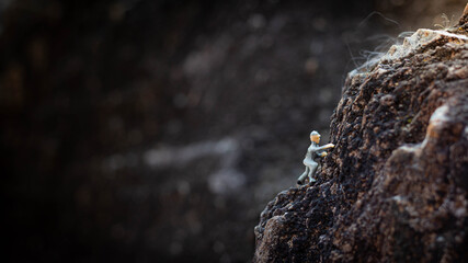 Miniature people : A man climbs a rocky cliff.