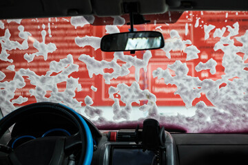Naklejka premium Foam on the windshield of the car, the view from the inside. Car wash.