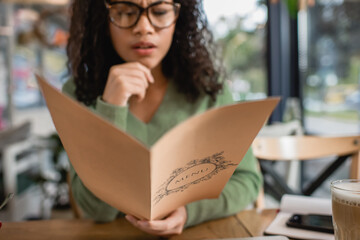Menu in hand of African American woman on blurred background