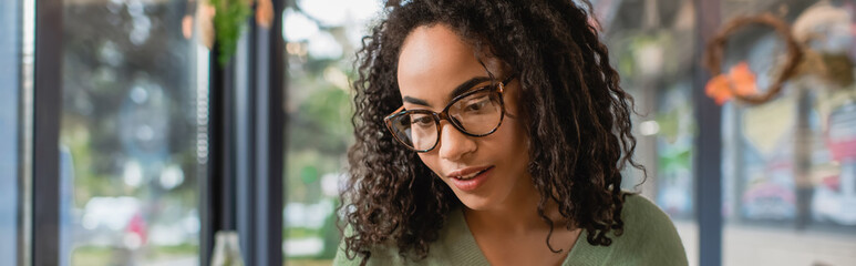 curly and young african american woman in glasses, banner