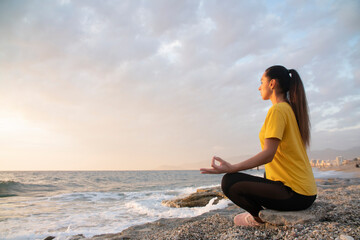 Fototapeta na wymiar Yoga woman in Lotus position practicing yoga and meditation. outdoors on the evening ocean
