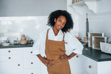 On the kitchen. Young african american woman with curly hair indoors at home