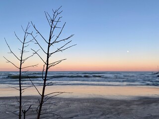 Fototapeta na wymiar Winter sunset at Gillson Beach on Lake Michigan's Illinois shore. A full moon is rising in the distance.