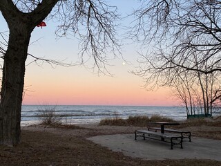 Fototapeta na wymiar Winter sunset at Gillson Beach on Lake Michigan's Illinois shore. A full moon is rising in the distance.
