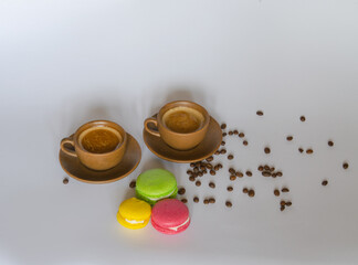 Colored macaroons and coffee in a cup on a light background
