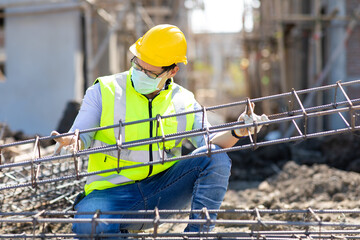 Asian construction worker on building site. fabricating steel reinforcement bar. wearing surgical...