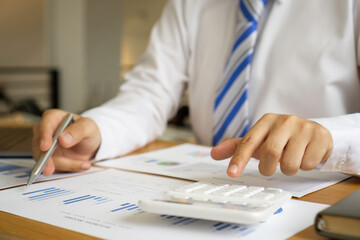 Asian finance staff is sitting at the table. By holding the calculator to calculate the profitability of the growing company, financial business ideas Corporate profit growth