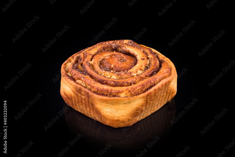 Wall mural Freshly baked sweet bun with raisins and cinnamon isolated on black background. Homemade traditional bakery, baking bread and sweets concept.