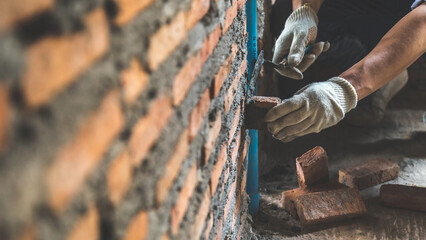Man bricklayer installing bricks on construction site - obrazy, fototapety, plakaty