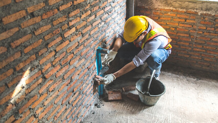 Man bricklayer installing bricks on construction site - obrazy, fototapety, plakaty