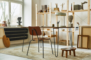 Unique artist workspace interior with stylish desk, wooden easel, bookcase, artworks, painting accessories, decoration and elegant personal stuff. Modern work room for artist. Template.