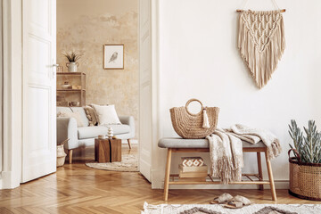 Scandinavian interior of open space with wooden bench, grey sofa, pillows, palid, picture frame, macrame, plant, books, carpet, shelf, decoration and elegant personal accessoreis in home decor.
