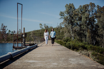 A couple of lovers walking hand in hand with a beautiful view in spring. White clothes she, the young man in blue. Newly married.