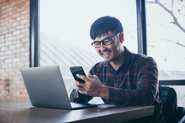 happy man work using texting cell phone typing computer.chatting on mobile,laptop contact us at workplace Thinking investment business plan.searching information.connecting people concept