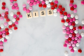 the word kiss written in scrabble tiles on a marble kitchen counter top surrounded by valentines candy