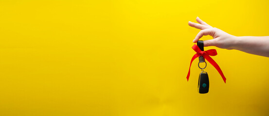 Woman's hand holds car keys. Car keys as a gift on a yellow background