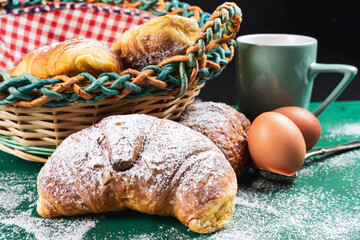 freshly baked croissants with powdered sugar on a rustic table