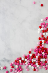 flat lay of red, white, and pink chocolate candies spilled onto a marble countertop