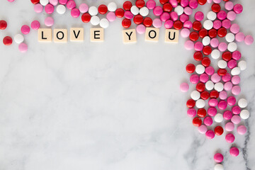 the words love you written in scrabble tiles on a marble kitchen counter top surrounded by valentines candy