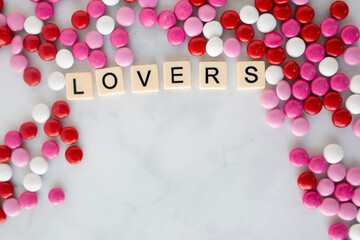 the words lover written in scrabble tiles on a marble kitchen counter top surrounded by valentines candy