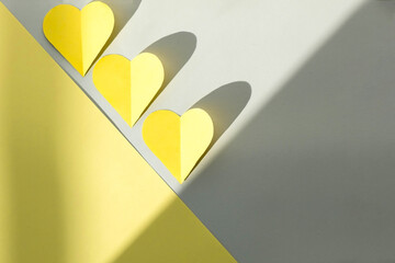 yellow hearts cut out of colored paper on a gray background, top view, colors 2021. Trendy colored valentines day concept.