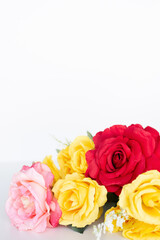 pink, red and yellow roses flat lay against a white background