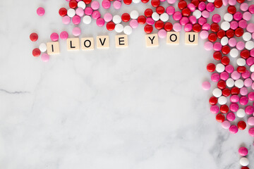the words i love you written in scrabble tiles on a marble kitchen counter top surrounded by valentines candy