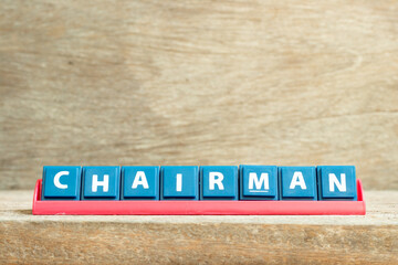 Tile letter on red rack in word chairman on wood background