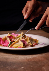 Hands cutting ravioli on the black background..Italian concept food.