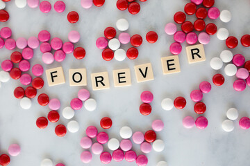 the word forever written in scrabble tiles on a marble kitchen counter top surrounded by valentines candy