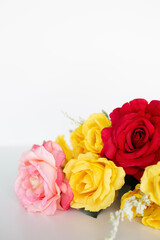 pink, red and yellow roses flat lay against a white background