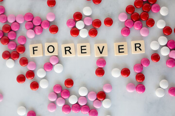the word forever written in scrabble tiles on a marble kitchen counter top surrounded by valentines candy