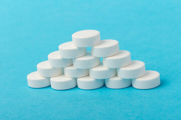 Heap of pills on blue background. Medicine, pharmacy and health concept.