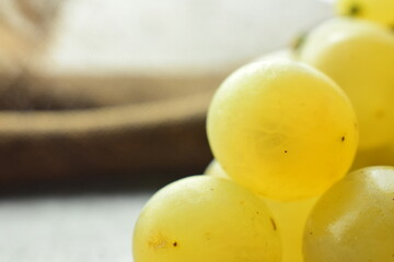 Macro, bunch of yellow grapes, with backlight and rustic fabric.