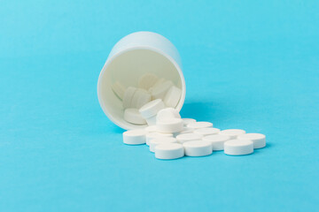 White tablets and bottle for tablets on blue background