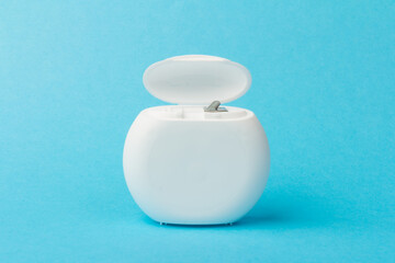 Dental floss container on blue background. Daily oral hygiene, teeth care and health. Cleaning products for your mouth, copy space. Dental care concept.