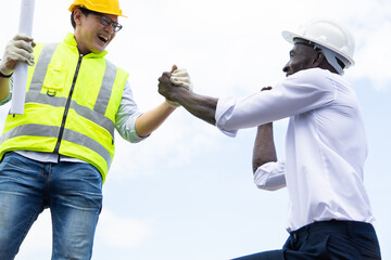 Architect and engineer construction worker shaking hands on construction site.