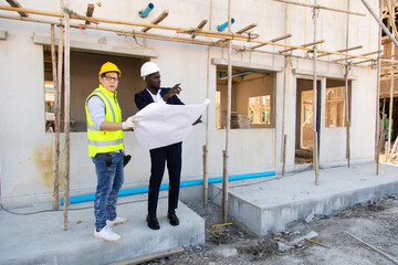 Professional Construction and  Engineer team Working on workplace. Professional black architect and construction worker working look at blueprint plan on site.