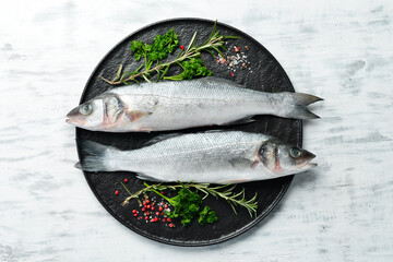 Raw sea bass fish with spices. On a white wooden background. Top view.