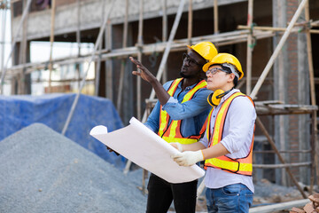 Professional Construction and  Engineer team Working on workplace. Professional black architect and construction worker working look at blueprint plan on site.