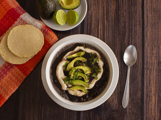 Salvadoran classic black beans soup with cream, avocado, and flat homemade tortilla 
