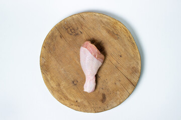 Raw chicken leg on a wooden board. One chicken leg on a white background. Chicken meat.