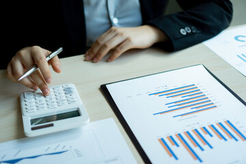 The female finance staff is calculating the company's profits from the graph on the home office desk. Concept finance