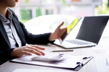 ..Female finance workers are using a calculator to calculate the company's earnings from a bar...