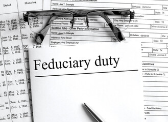 Paper with text Feduciary duty on a financial table with eyeglasses and metal pen