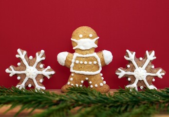 Gingerbread man with protective face mask, snowflakes and spruce twig. Original Christmas or New year concept. Coronavirus winter