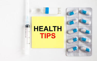 Yellow sticker with text Health Tips on a white background with syringes, pills and ampoule.