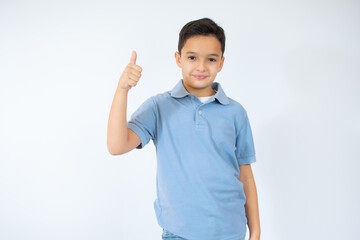 Happy child, little boy showing thumbs up gesture in a blue T-shirt isolated on white background